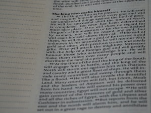 A close-up image of a page from a book or document, featuring English text printed in a block format. The text is densely packed with paragraphs and headings in bold, indicating different sections. The paper is light-colored, and the text is black with a readable, standard font. On the left side, there is a margin with evenly spaced dotted lines.