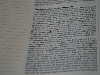 A close-up image of a page from a book or document, featuring English text printed in a block format. The text is densely packed with paragraphs and headings in bold, indicating different sections. The paper is light-colored, and the text is black with a readable, standard font. On the left side, there is a margin with evenly spaced dotted lines.