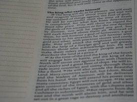 A close-up image of a page from a book or document, featuring English text printed in a block format. The text is densely packed with paragraphs and headings in bold, indicating different sections. The paper is light-colored, and the text is black with a readable, standard font. On the left side, there is a margin with evenly spaced dotted lines.