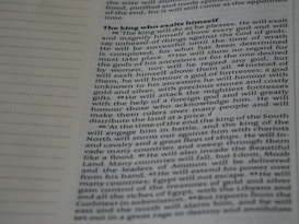 A close-up image of a page from a book or document, featuring English text printed in a block format. The text is densely packed with paragraphs and headings in bold, indicating different sections. The paper is light-colored, and the text is black with a readable, standard font. On the left side, there is a margin with evenly spaced dotted lines.
