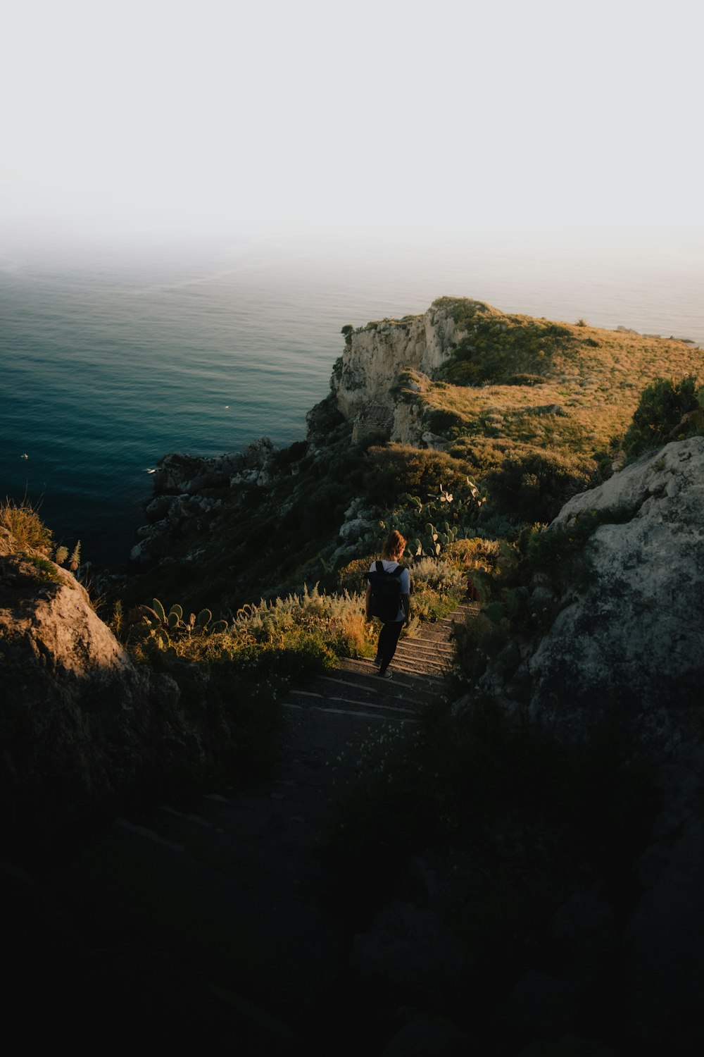 a person walking up a steep hill next to the ocean