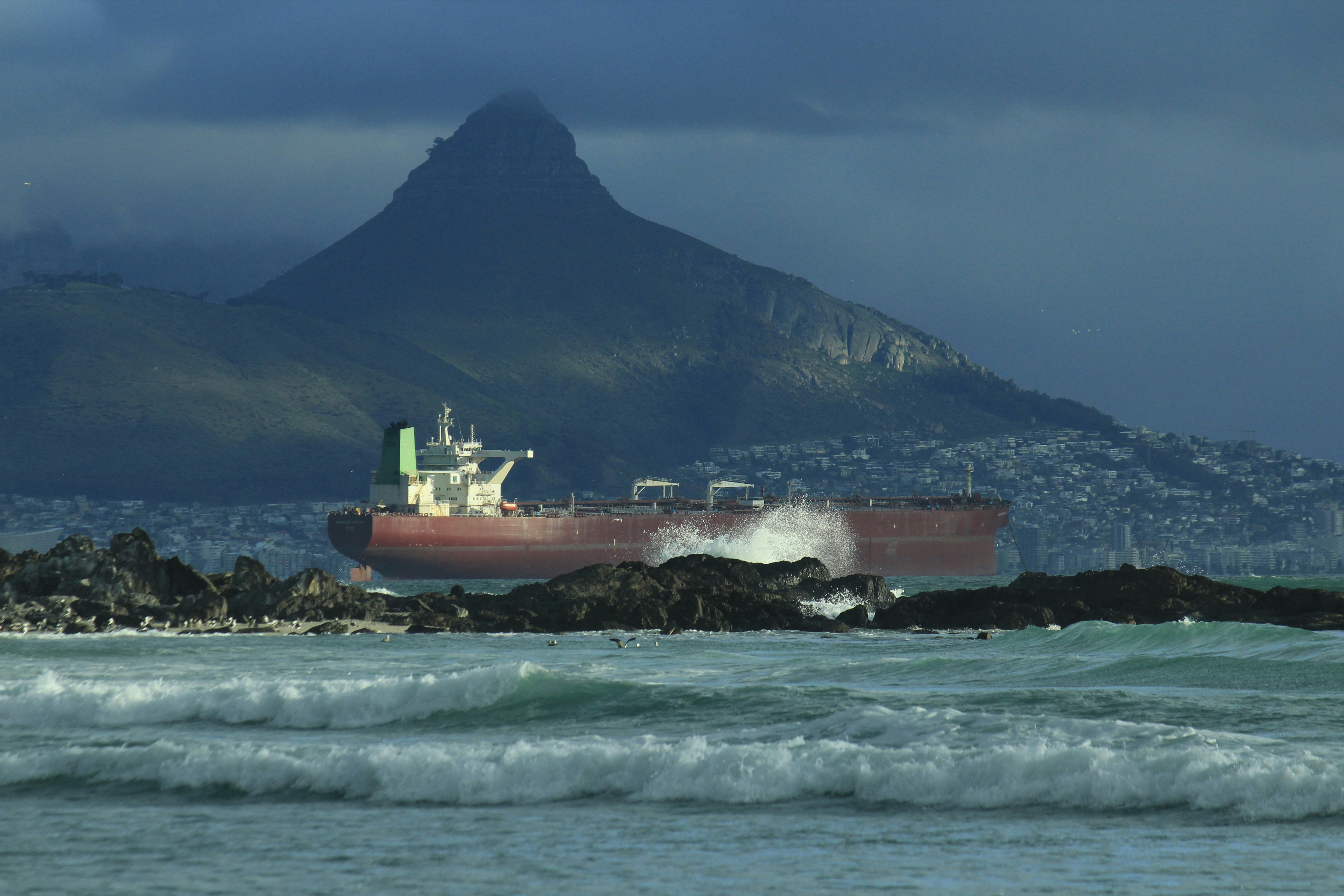 a large cargo ship in the ocean with a mountain in the background, 