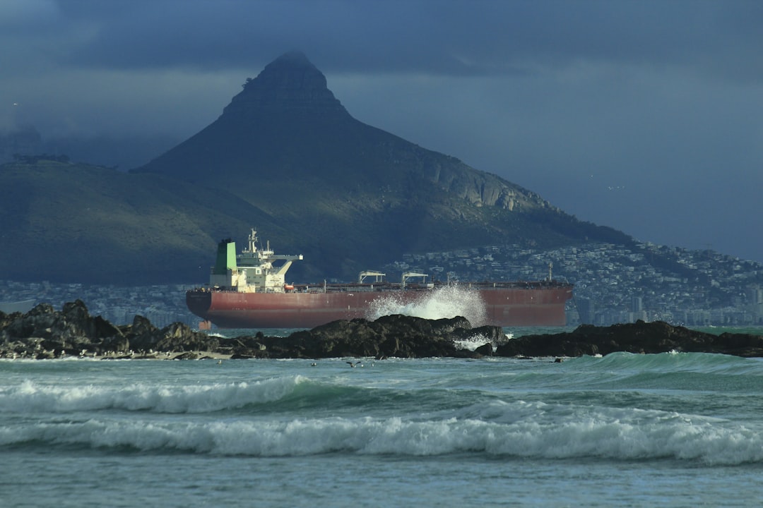 a large cargo ship in the ocean with a mountain in the background,