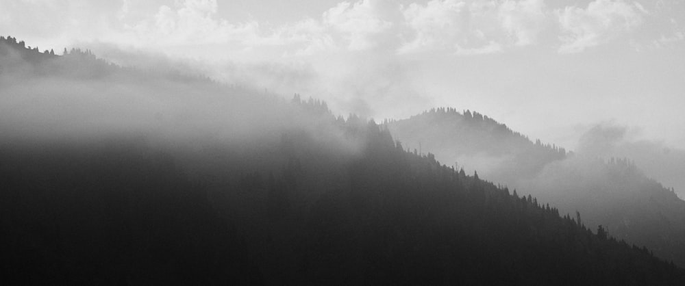 a black and white photo of a foggy mountain