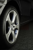 A close-up view of a car wheel with a silver alloy rim and a black tire featuring the Michelin logo. The floor beneath the car appears to be tiled.