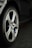 A close-up view of a car wheel with a silver alloy rim and a black tire featuring the Michelin logo. The floor beneath the car appears to be tiled.