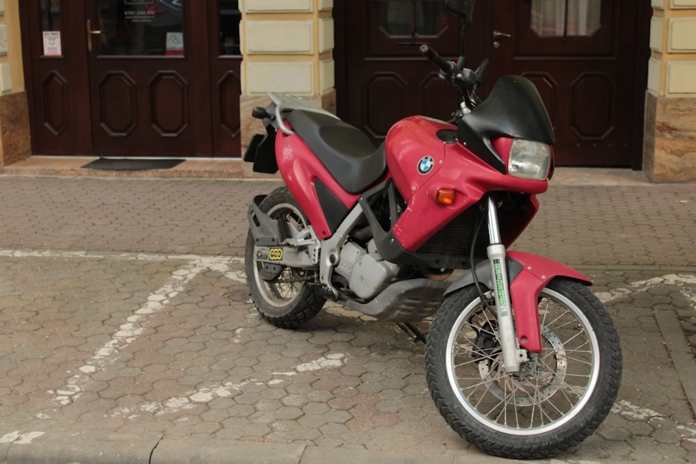 a red motorcycle parked in front of a building