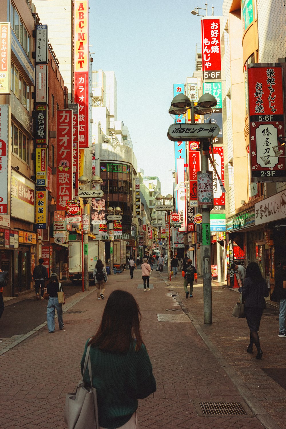 a woman walking down a street next to tall buildings