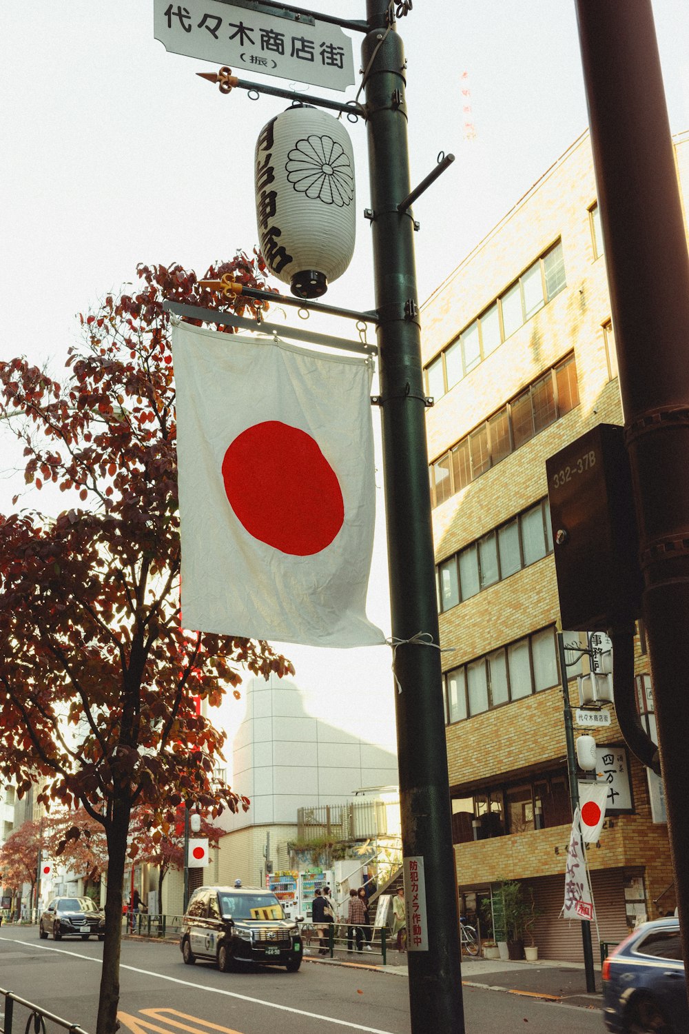 a street sign with a japanese flag hanging from it's pole