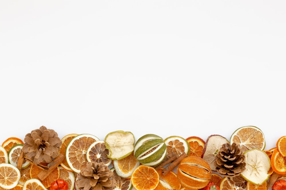a group of sliced oranges, apples, and pine cones