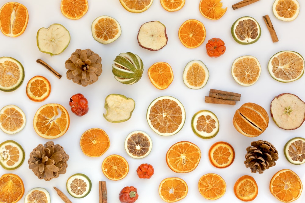 orange slices, cinnamons, and pine cones arranged on a white surface
