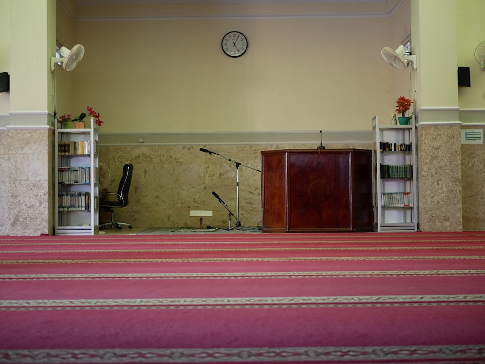 a room with a red carpet and a clock on the wall