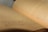 A close-up view of an open book with Arabic text. The pages are curved and the focus is on the middle of the book, with the background slightly blurred.