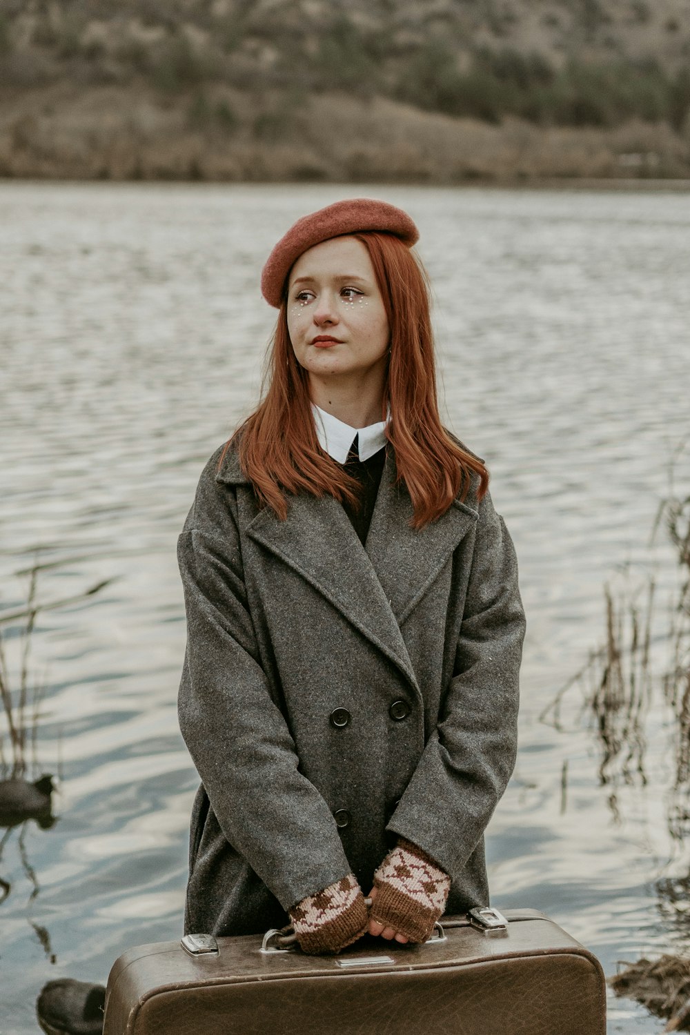 a woman standing next to a suitcase near a body of water