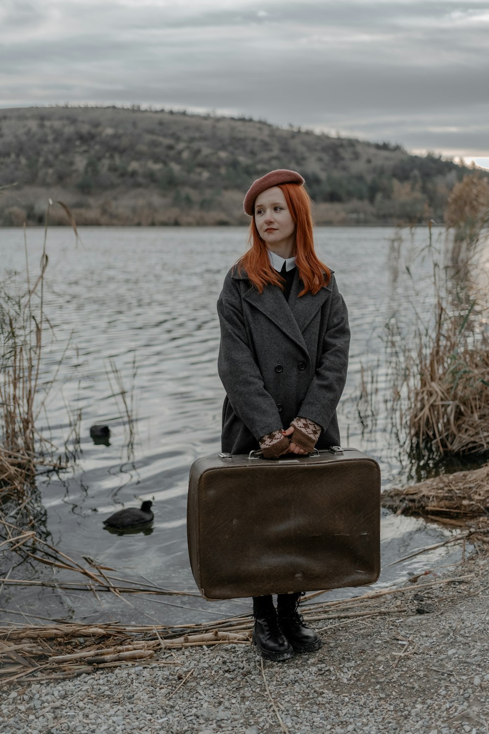 a woman with red hair is holding a suitcase