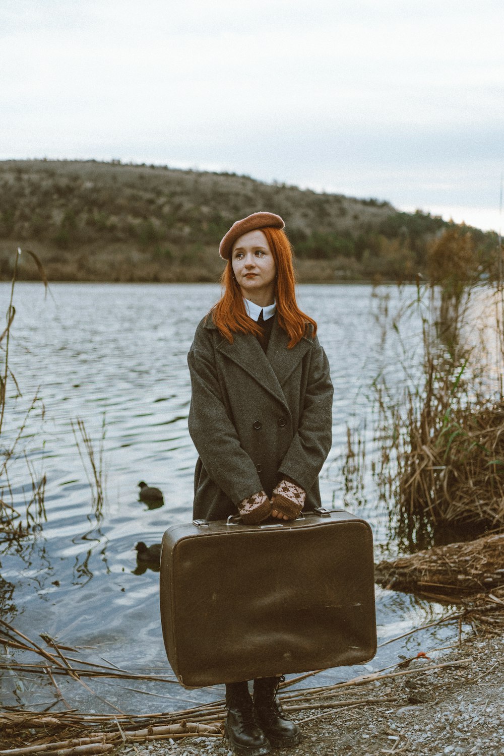 a woman with red hair is holding a suitcase