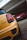 A close-up view of a yellow car with Union Jack-themed taillights parked in focus, while a red car is seen parked further inside a garage. Both vehicles are parked on a tiled and paved driveway under a white structure.
