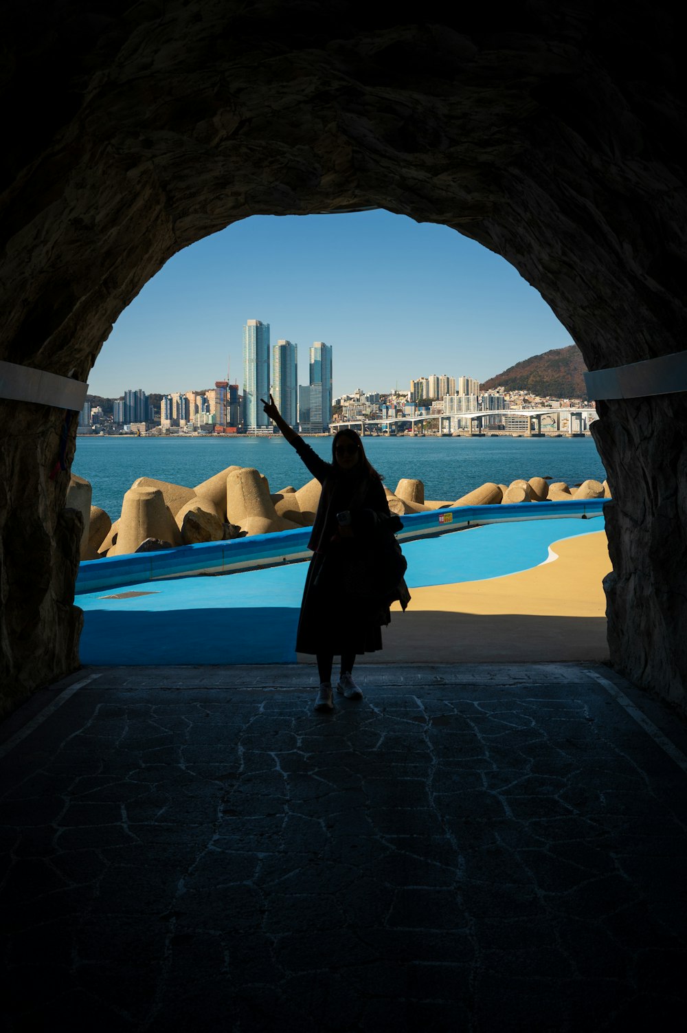 a woman standing in a tunnel with a city in the background