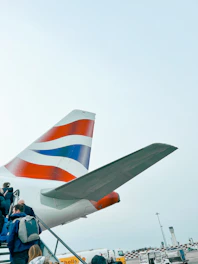 A happy group of travelers boarding a plane with bright blue and turquoise accents in the background.