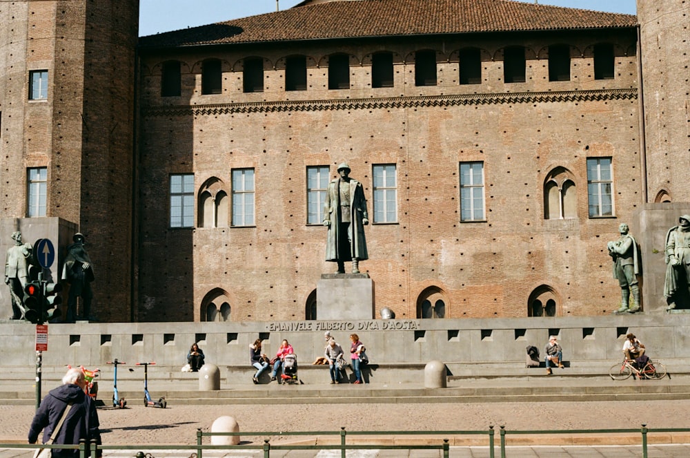 a group of people sitting and standing in front of a building