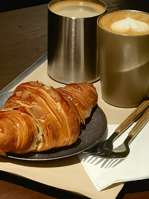 Freshly baked croissants and avocado toast served on rustic plates.