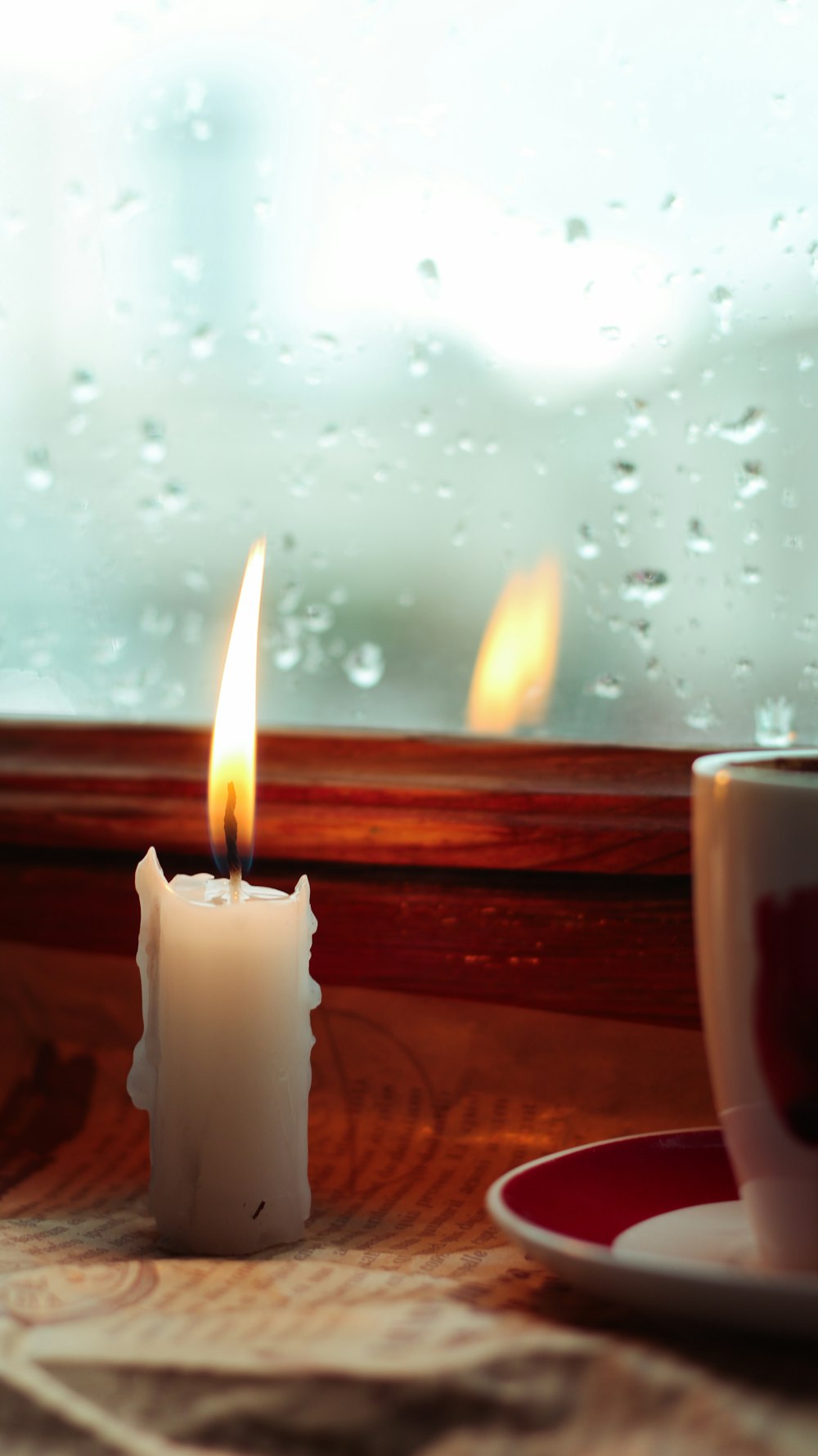 a candle sitting on a table next to a cup of coffee