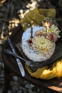 A beautifully decorated birthday cake with fresh flowers on a rustic wooden table.