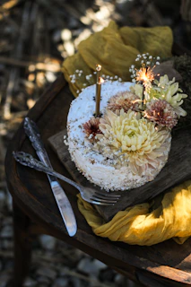 A beautifully decorated pink and gold cake on a rustic wooden table with soft natural lighting.