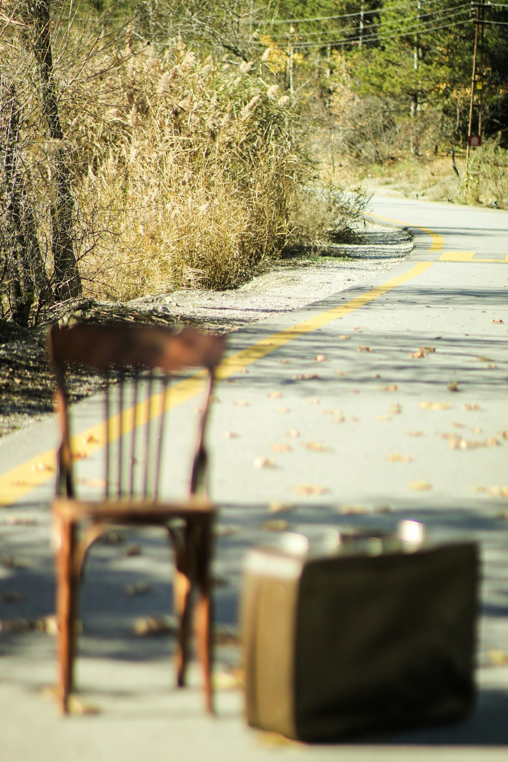 a chair sitting on the side of a road next to a suitcase