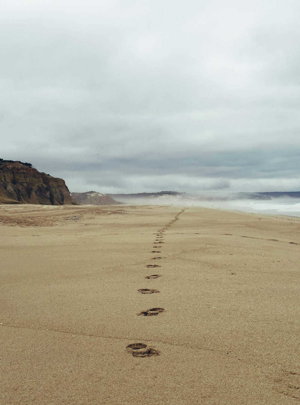 a person walking on a beach with footprints in the sand