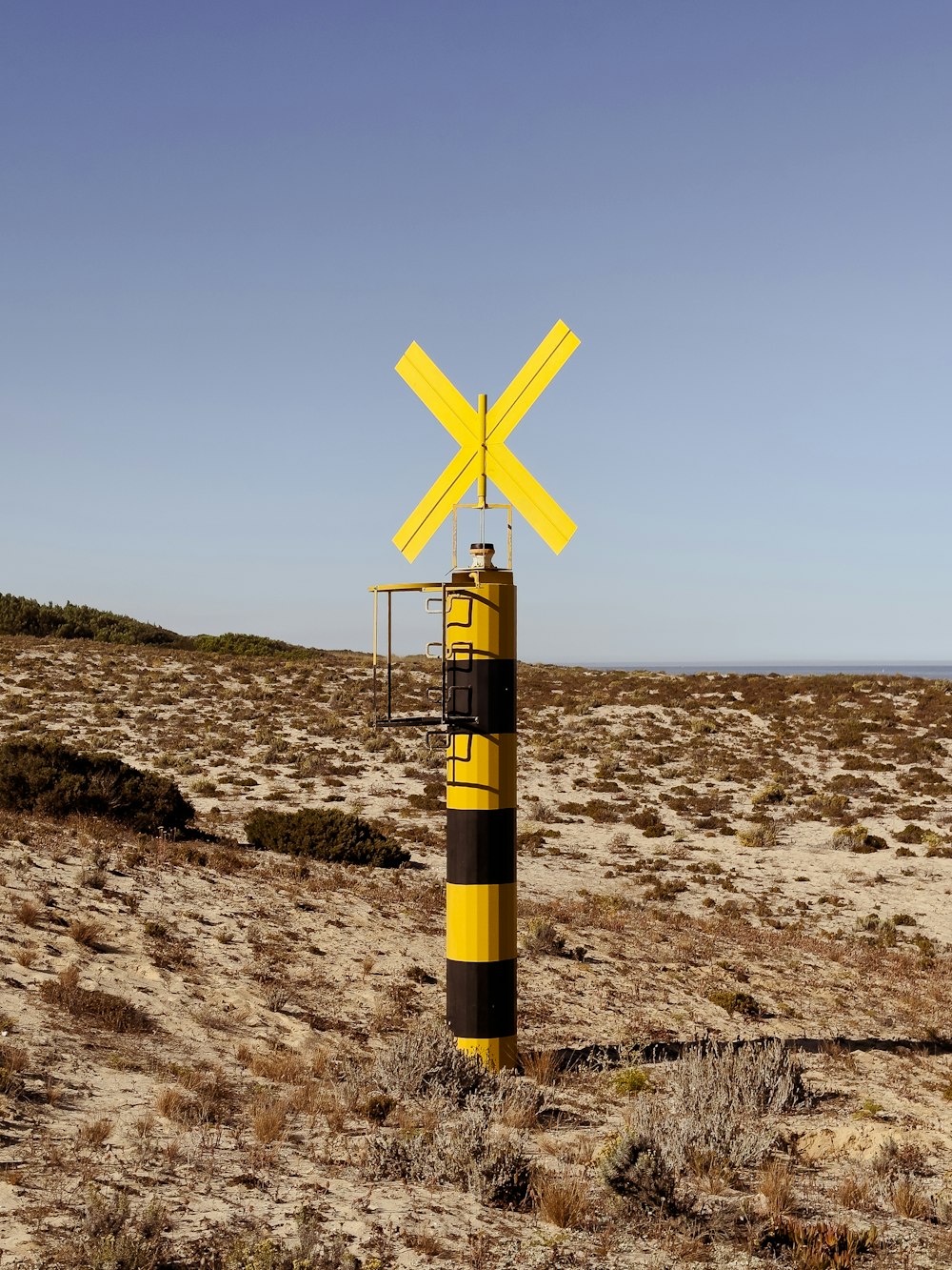 a yellow and black pole in the middle of a desert