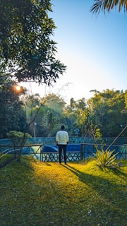 A handyman painting a white fence in a sunny garden.