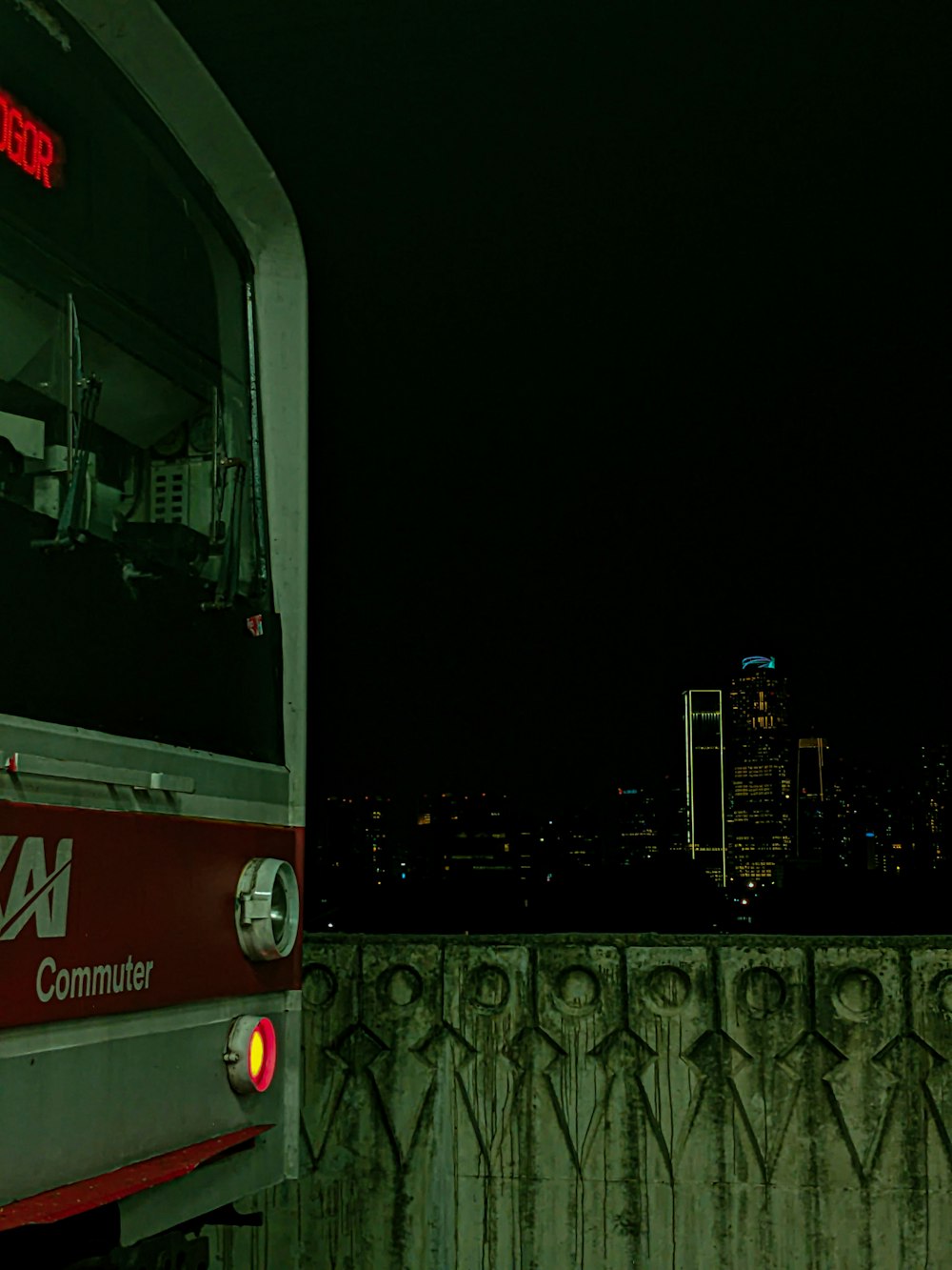 a red and white train traveling past a tall building