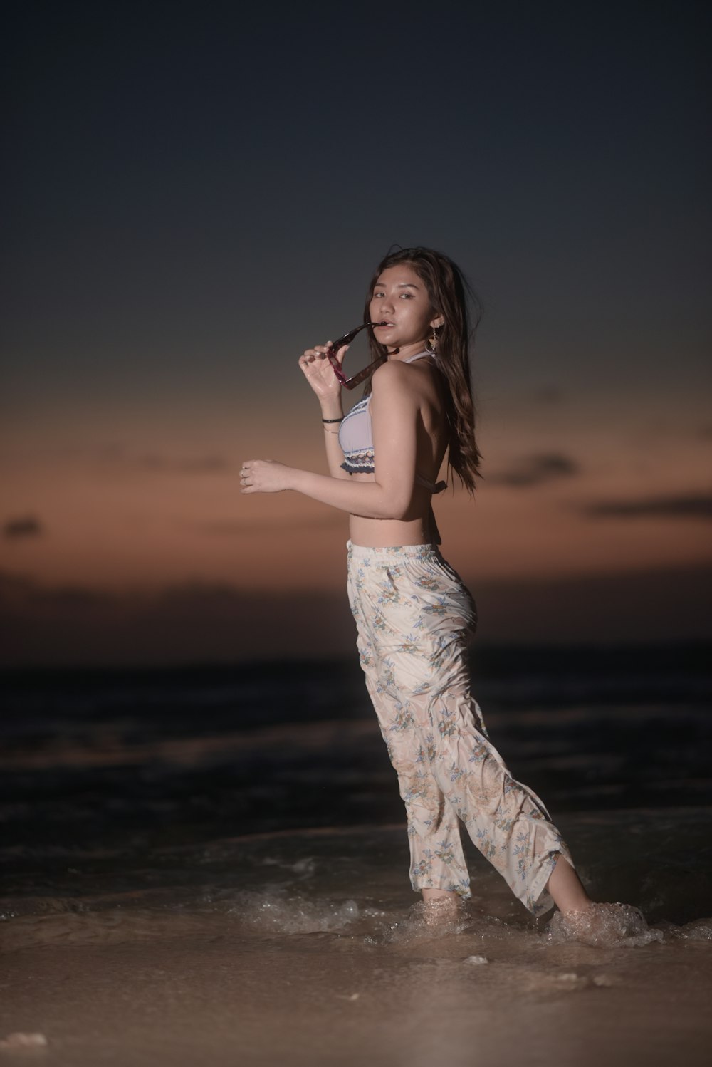 a woman standing on top of a beach next to the ocean