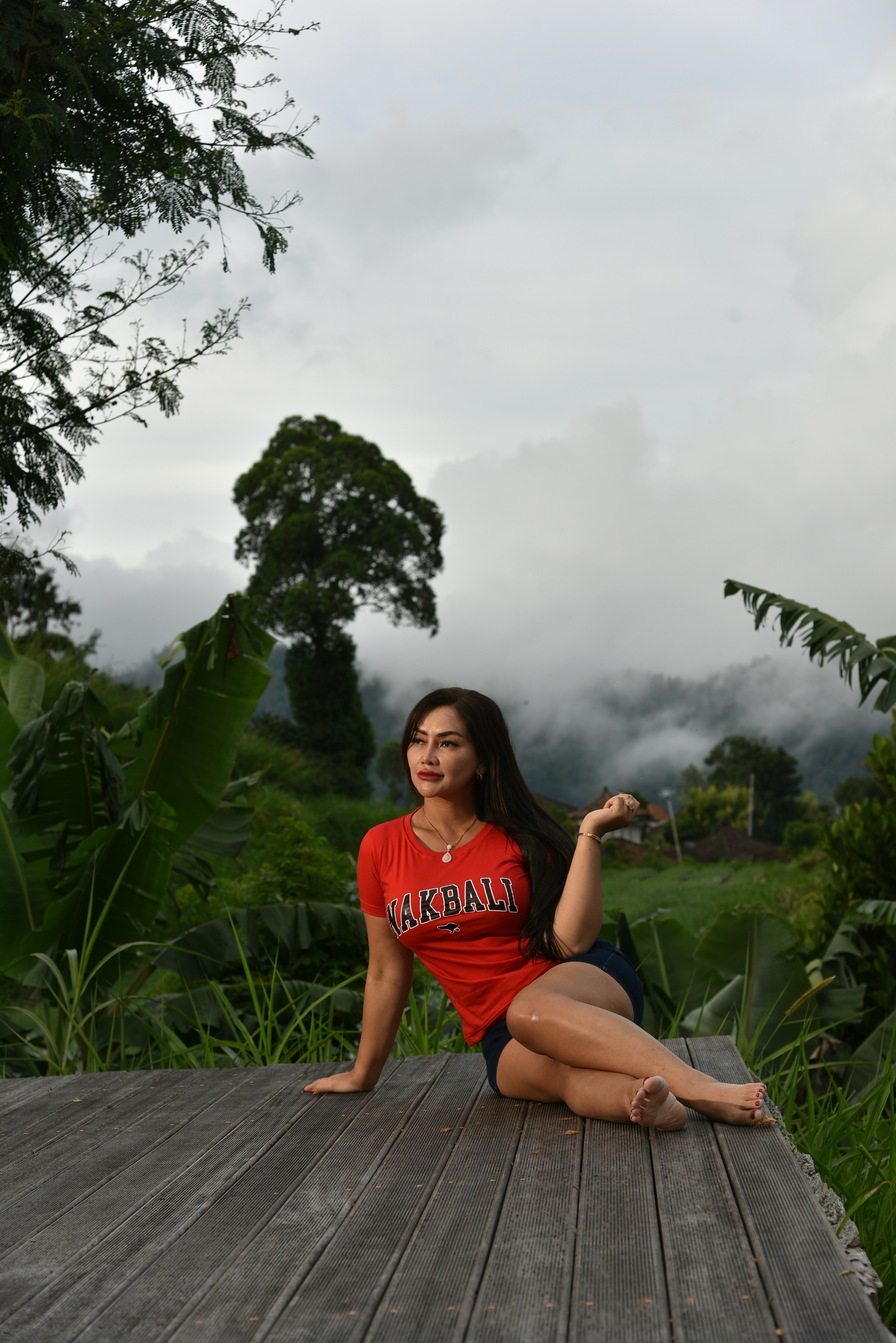 seorang wanita duduk di dek kayu dengan kemeja merah