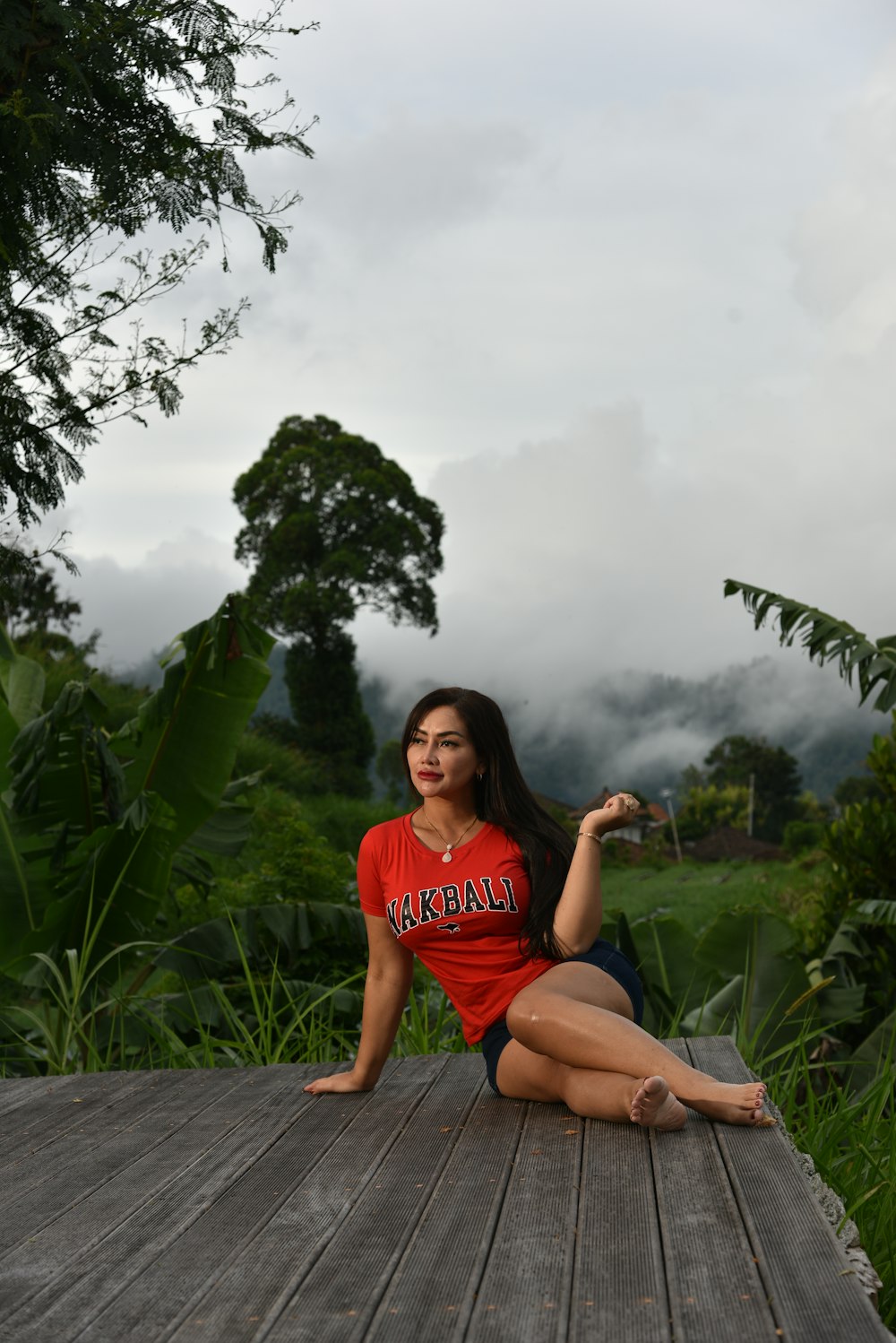 a woman sitting on a wooden deck in a red shirt