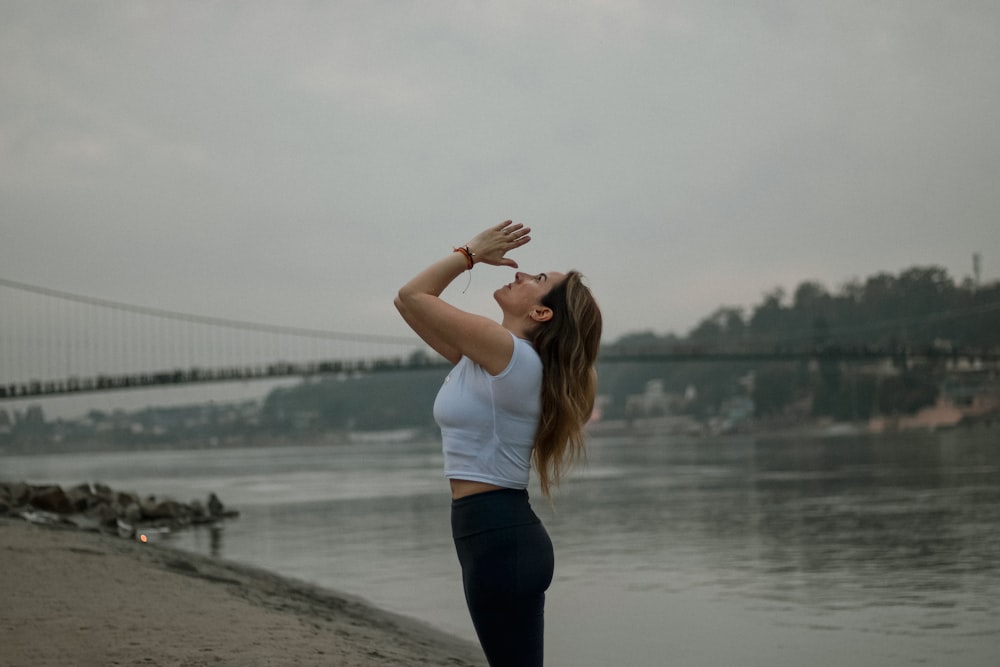 a woman standing on a beach next to a body of water