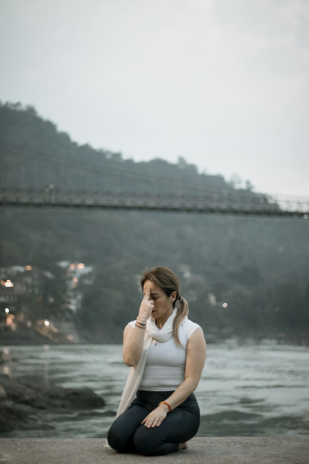 a woman sitting on the ground in front of a river