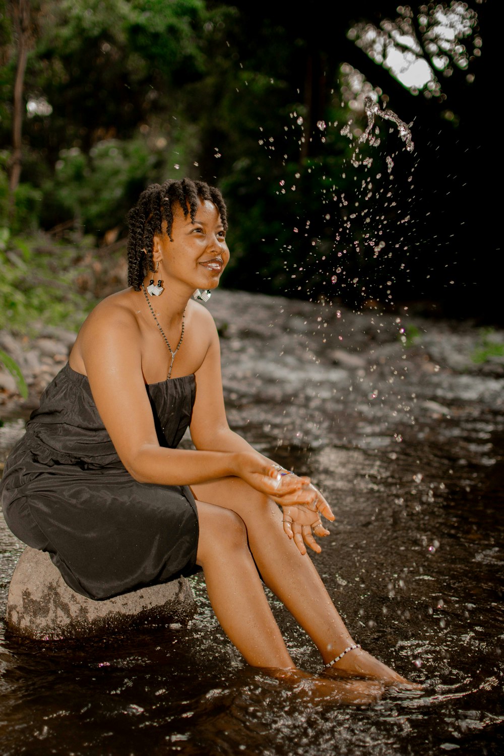 a woman sitting on a rock in the water