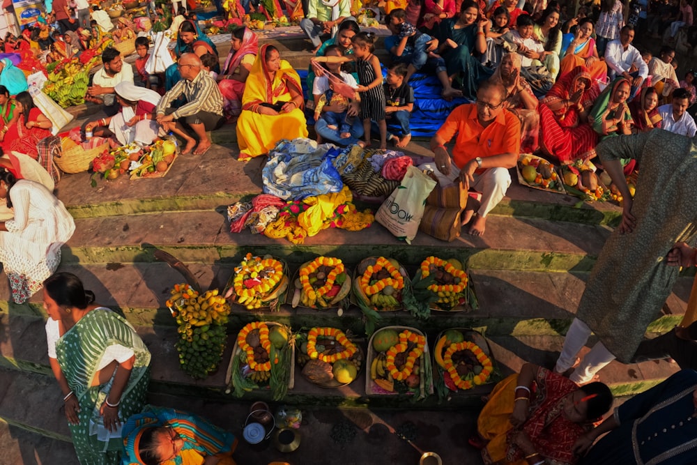 a group of people sitting around a table filled with fruits and vegetables