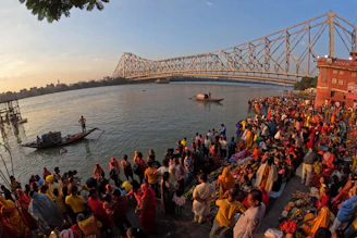 a crowd of people standing on the side of a river