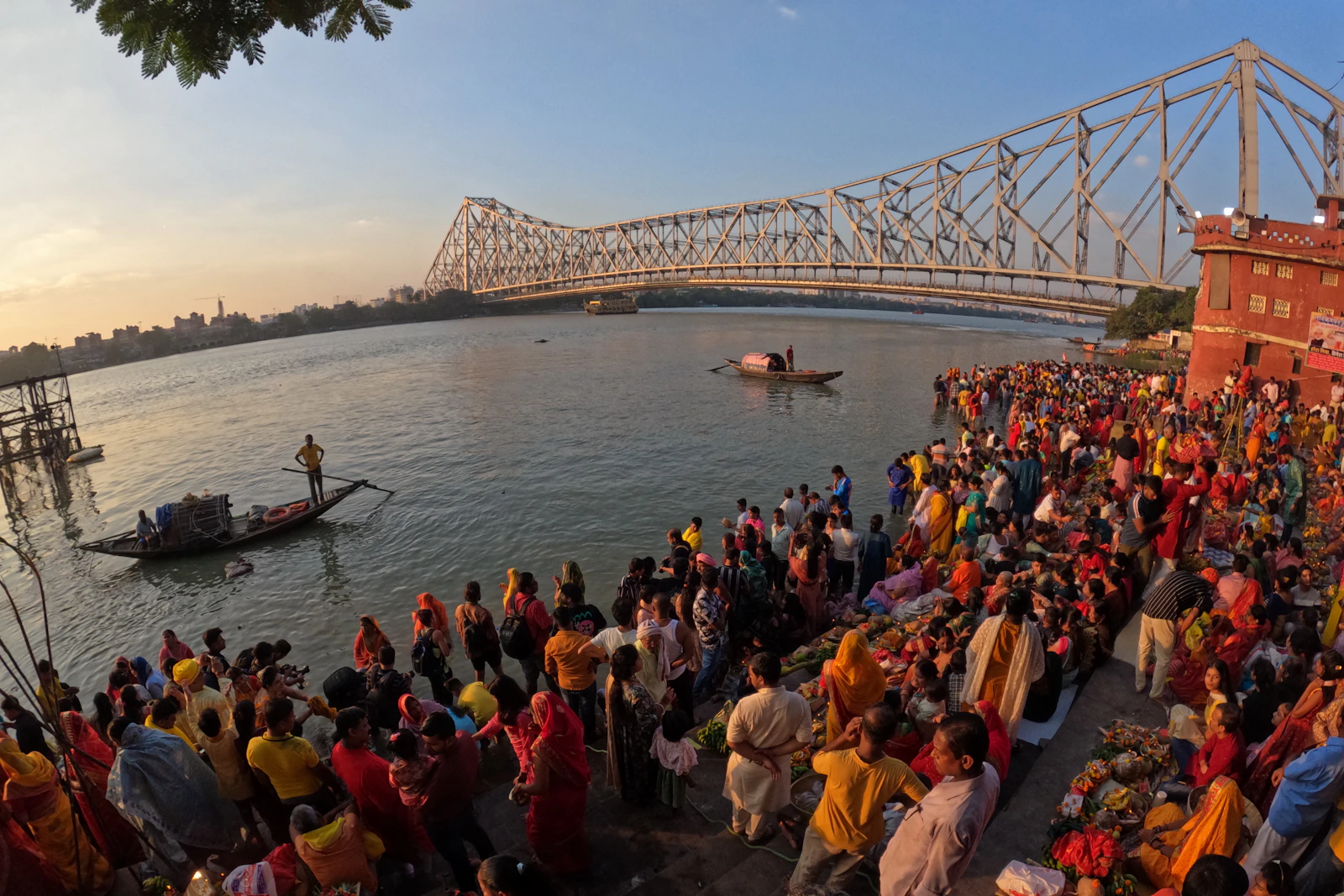 कोलकाता में नदी किनारे जुटे श्रद्धालु, पीछे हावड़ा ब्रिज।