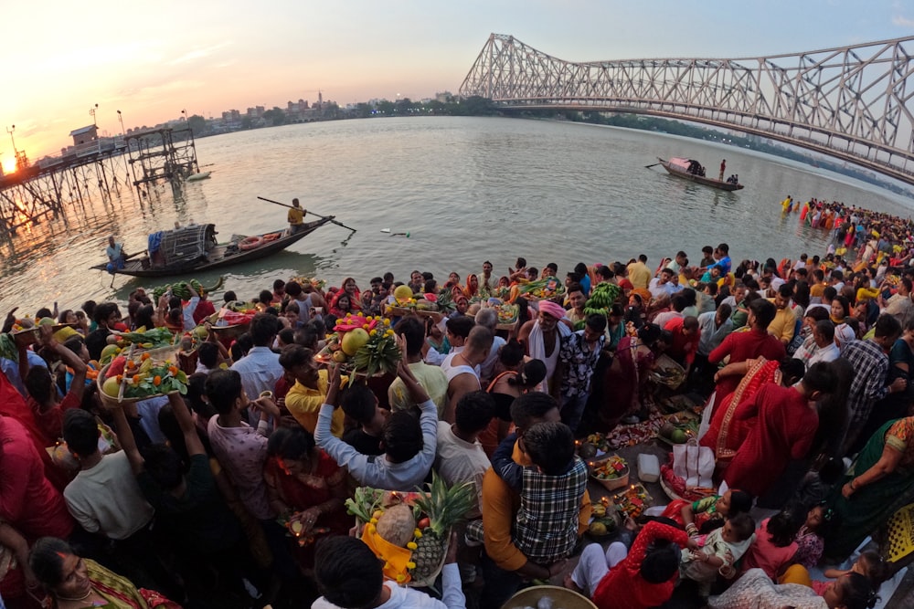 a large group of people sitting on the side of a river