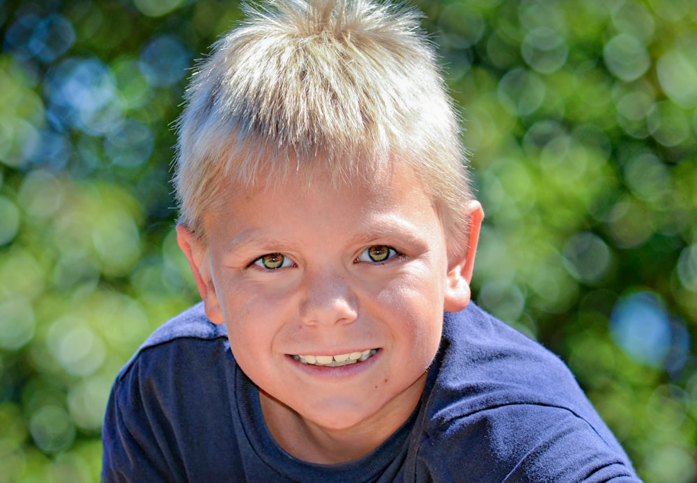 a young boy with blonde hair and a blue shirt