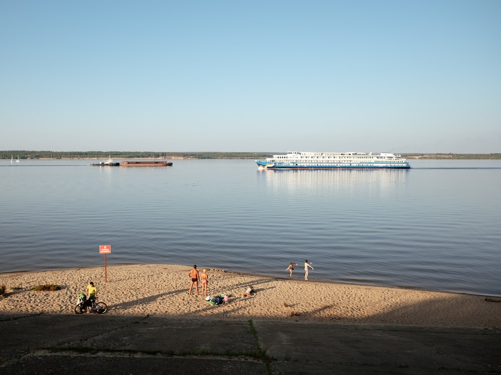 a group of people standing on a beach next to a body of water