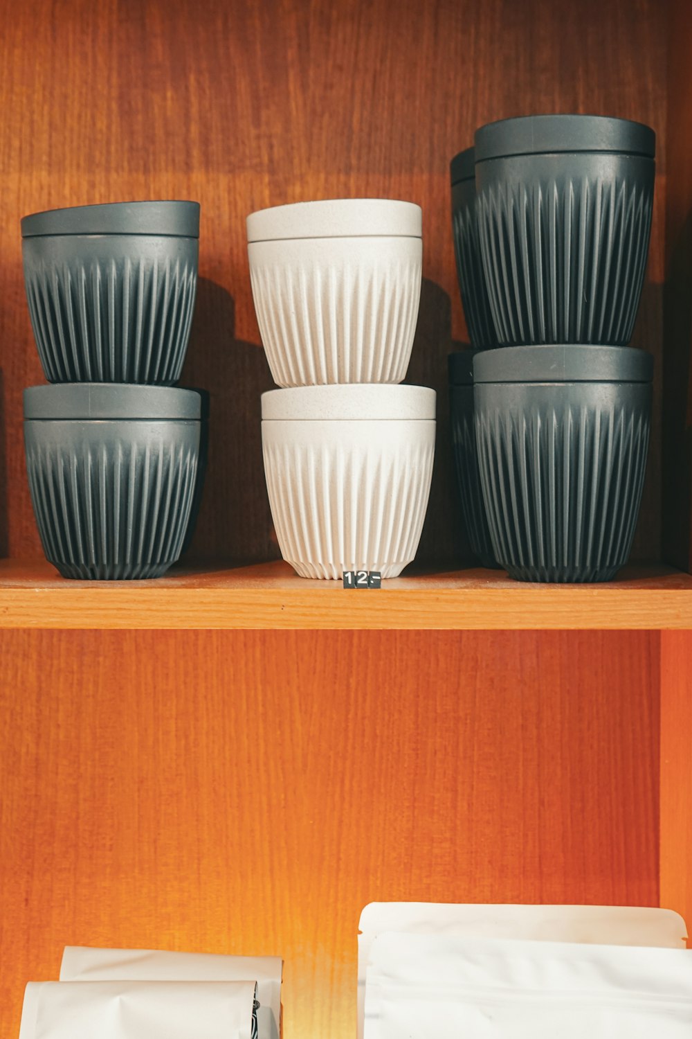 a shelf filled with lots of white and black cups