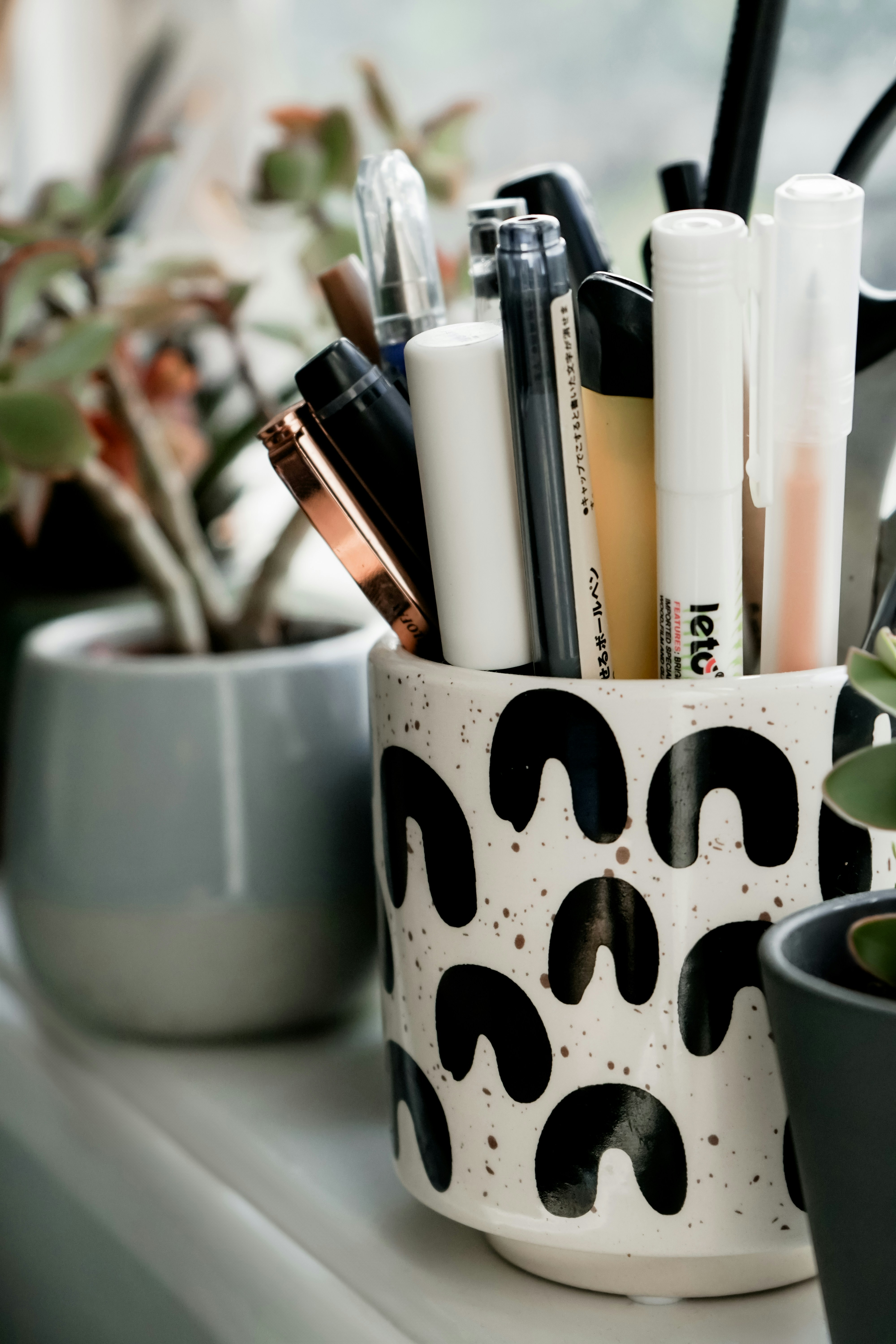 a white cup filled with lots of different types of pens
