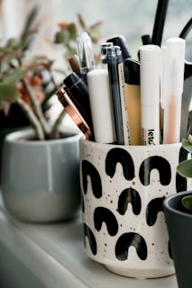A collection of eco-friendly pens and markers laid out on a recycled paper notebook.