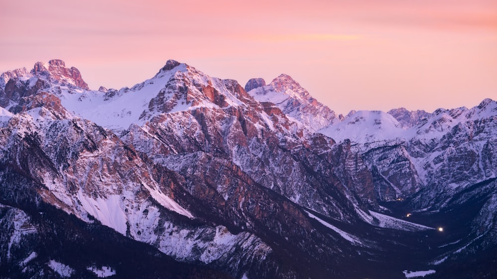 the mountains are covered in snow at sunset