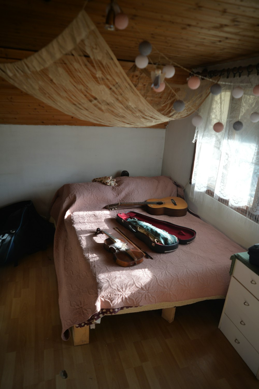 a bedroom with a bed, dresser and a window